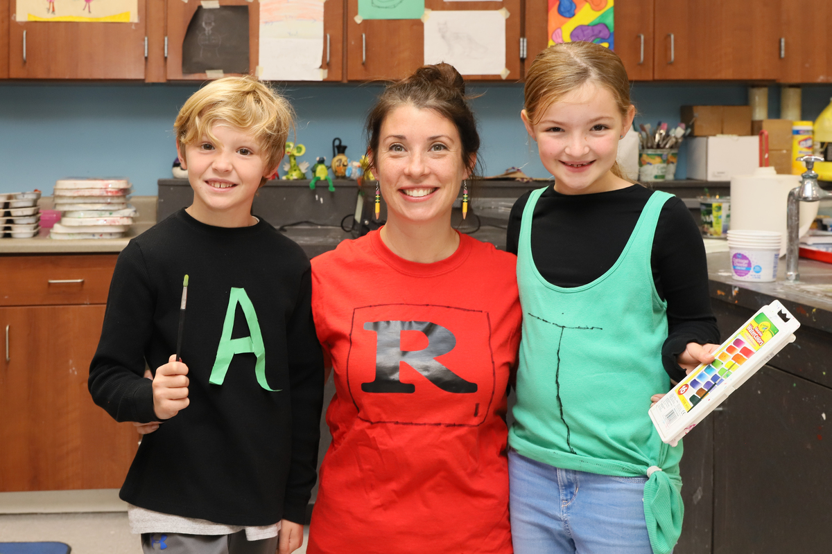 Students and a teacher wear shirts that spell out "art"